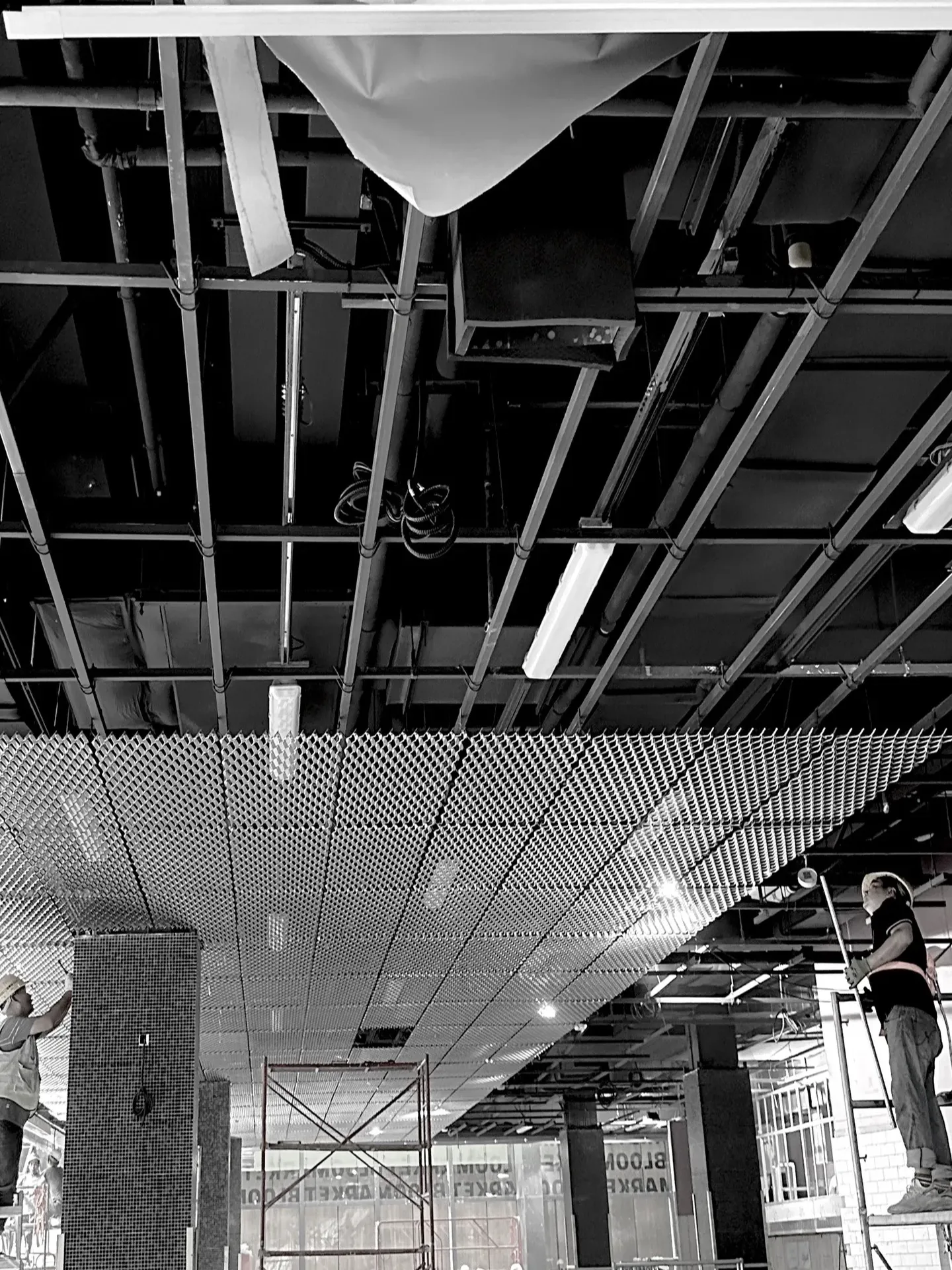 Metal mesh ceiling panels being installed in an interior