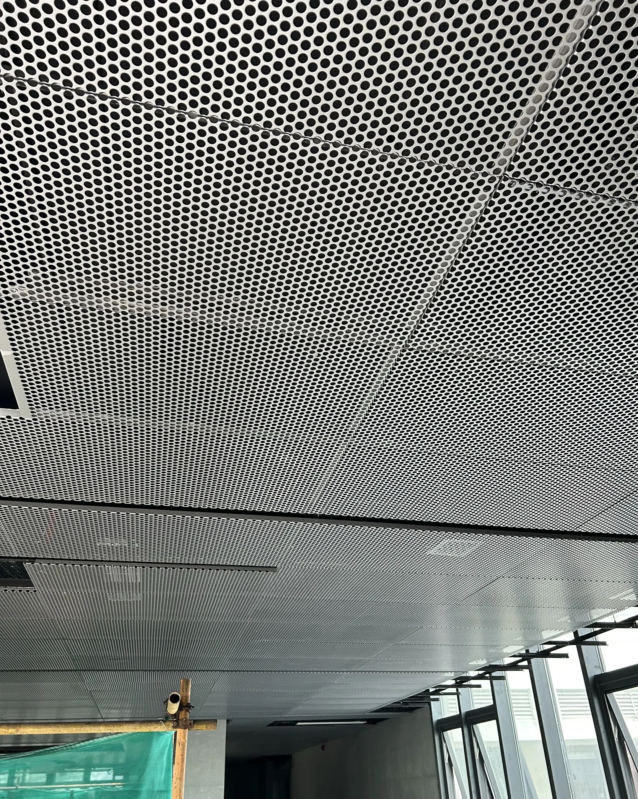 Installed white perforated metal ceiling panels in a modular grid