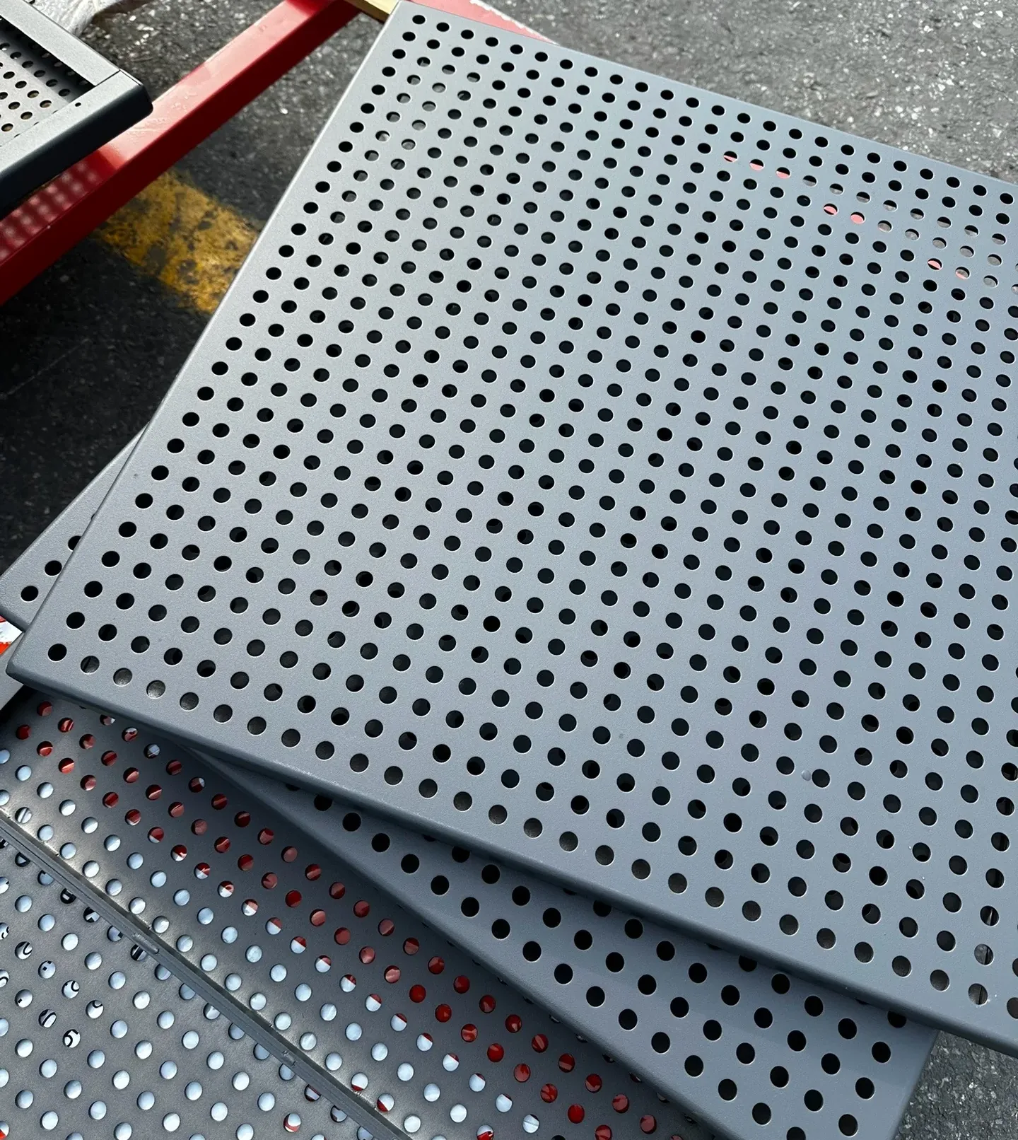 Stack of dark perforated metal panels showing repeated round holes